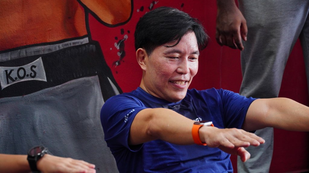 Man smiling while performing sit-ups at King of Strength boxing gym.